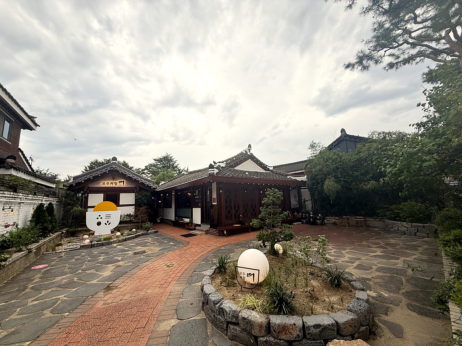 돌담 화단과 달 조형물이 있는 정원 진입로 · The garden path with its stone flower beds and the moon