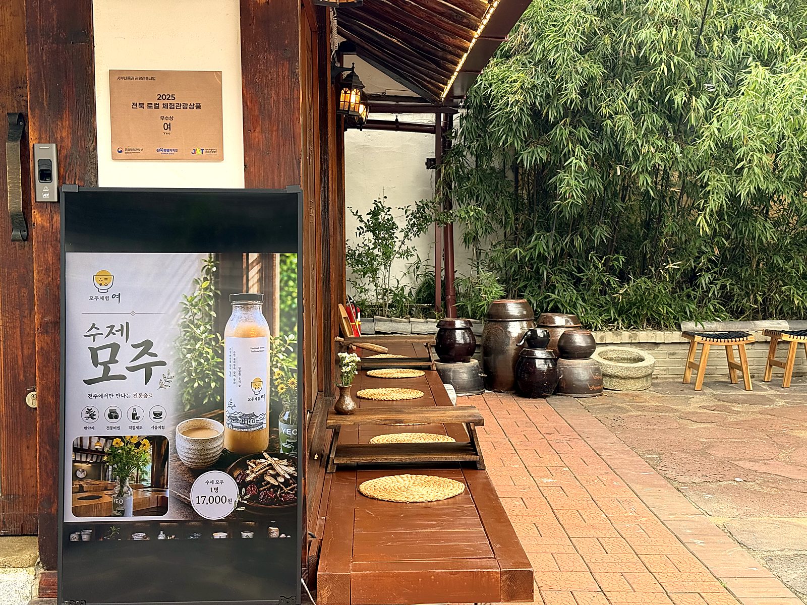 입구의 수제 모주 포스터와 2025 전북 로컬 체험관광상품 우수상 명판 · The poster at the entrance and the 2025 award plaque